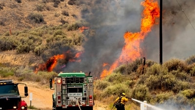 A firefighter vehicle tries to contain the Madre Fire as it races along Highway 166 in San Luis Obispo County on July 3, 2025. (AP Photo/Noah Berger) (AP)