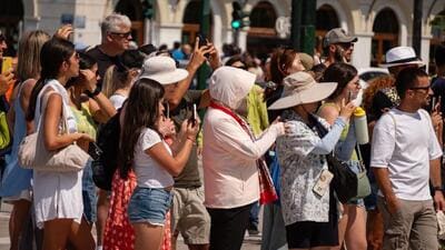 Tourists shield themselves from the beating sun in Athens, Greece. (Bloomberg) Tourists shield themselves from the beating sun in Athens, Greece. (Bloomberg)