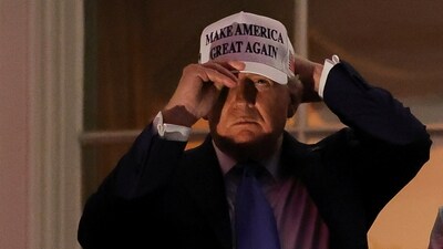 US President Donald Trump holds his cap as he stands at a balcony at the White House in Washington, DC, (REUTERS)