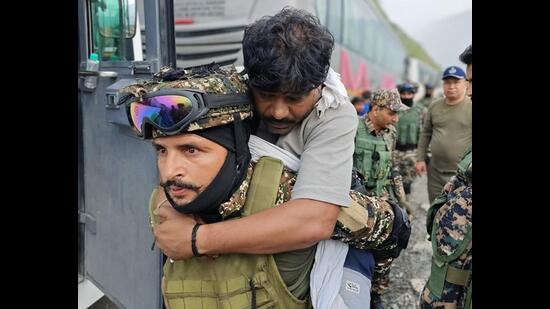 A securityman carries an injured after the mishap in Chanderkote area of Ramban on Saturday. (HT photo)
