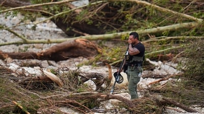 A Sheriff's deputy pauses while combing through the banks of the Guadalupe River near Camp Mystic after a flash flood swept through the area. (AP Photo/Julio Cortez) A Sheriff's deputy pauses while combing through the banks of the Guadalupe River near Camp Mystic after a flash flood swept through the area. (AP Photo/Julio Cortez)