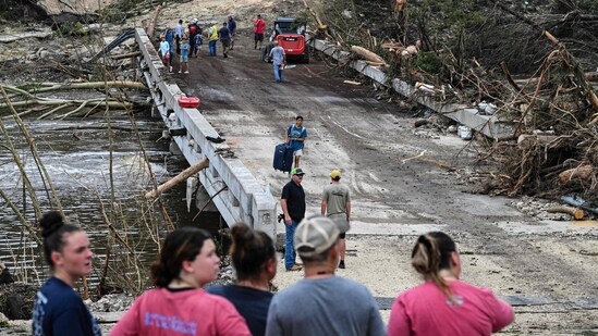 People look on as law enforcement and volunteers continue to search for missing people near Camp Mystic, the site of where at least 20 girls went missing after flash flooding in Hunt, Texas.(AFP/Ronaldo Schemidt)