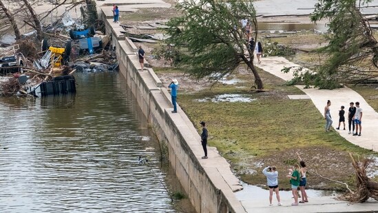 Onlookers walk along the banks of the Guadalupe River in Louise Hays Park, Saturday, July 5, 2025, in Kerrville, Texas.(AP Photo/Rodolfo Gonzalez)