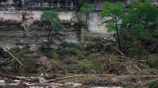 A Texas Department of Public Safety official, bottom left, combs through the banks of the Guadalupe River near Camp Mystic after a flash flood swept through the area Saturday, July 5, 2025, in Hunt, Texas.(AP Photo/Julio Cortez)