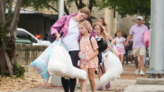 A woman and a child embrace after girls from Camp Waldemar, near the North fork of the Guadalupe River, are reunited with their families after heavy rainfall in Central Texas.(AP Photo)