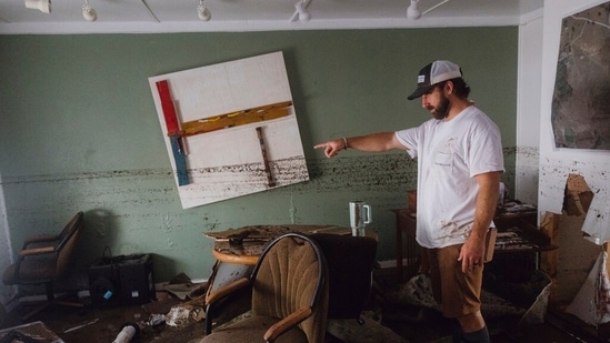 Garrett Burleson shows the damage to the office of his family's architectural business as a dirt line shows the extent of the flooding that the building faced, in Ingram.(AP)