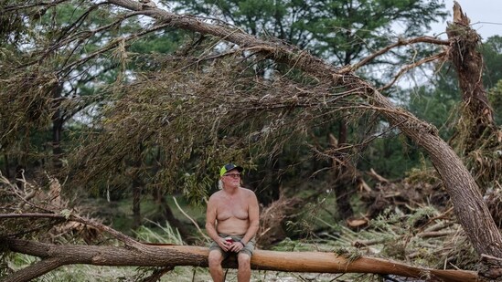 Kyle Hammock sits on tree debris at the bank Guadalupe River on July 5, 2025 in Center Point, Texas. Heavy rainfall caused flooding along the Guadalupe River in central Texas with multiple fatalities reported.(AFP)