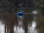 Rescuers paddle an inflatable boat as they search along a waterway following flash flooding, in Kerrville, Texas.