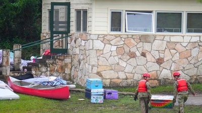 Military personnel return a camp trunk salvaged from downriver to Camp Mystic along the Guadalupe River after a flash flood swept through the area in Hunt, Texas. (AP) Military personnel return a camp trunk salvaged from downriver to Camp Mystic along the Guadalupe River after a flash flood swept through the area in Hunt, Texas. (AP)