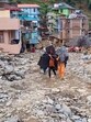 Locals carry their belongings as they walk amid the debris at a flood-affected area, at Thunag in Mandi district on Monday. (PTI) Locals carry their belongings as they walk amid the debris at a flood-affected area, at Thunag in Mandi district on Monday. (PTI)