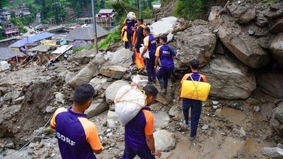 NDRF personnel carry relief materials to distribute to villagers at the cloudburst-affected areas, in Himachal Pradesh's Mandi (ANI) NDRF personnel carry relief materials to distribute to villagers at the cloudburst-affected areas, in Himachal Pradesh's Mandi (ANI)