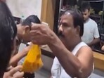 Sanjay Gaikwad, from the Shiv Sena of deputy CM Eknath Shinde, holding up the "stale" dal as he goes on to slap a staff member at the MLA Hostel canteen in Mumbai. 