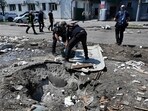 Ukrainian law enforcement officers work next to a crater following a drone attack in Kharkiv. Ukrainian law enforcement officers work next to a crater following a drone attack in Kharkiv.