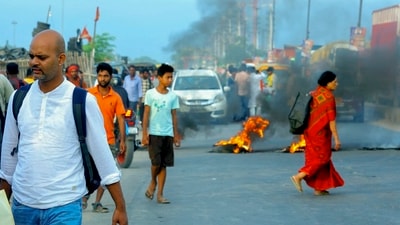 People pass by burning tyres amid 'Bihar bandh' called by the INDIA bloc against Special Intensive Revision in the state, in Hajipur, Bihar. Special Intensive Revision is aimed at revising the voter list in Bihar ahead of the upcoming assembly elections. (PTI)