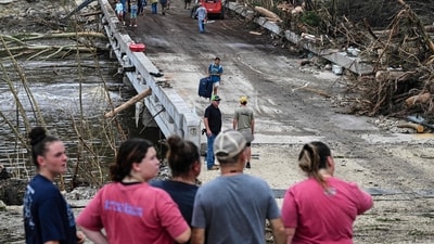 People look on as law enforcement and volunteers continue to search for missing people near Camp Mystic (AFP) People look on as law enforcement and volunteers continue to search for missing people near Camp Mystic (AFP)