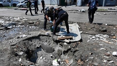 Ukrainian law enforcement officers work next to a crater following a drone attack in Kharkiv. (AFP) Ukrainian law enforcement officers work next to a crater following a drone attack in Kharkiv. (AFP)