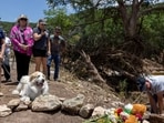 At least 27 people have died in the flash floods at Camp Mystic, Texas. People honour those who lost their lives with flowers and a cross placed near the Guadalupe River.