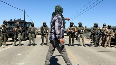 A demonstrator walks in front of federal agents blocking a road during an immigration raid in Camarillo (AP/Michael Owen Baker) A demonstrator walks in front of federal agents blocking a road during an immigration raid in Camarillo (AP/Michael Owen Baker)
