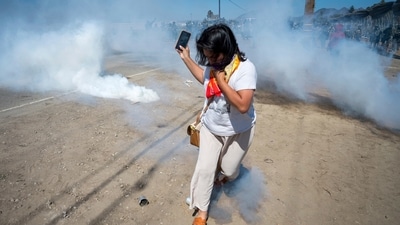 A protester runs from tear gas tossed by federal immigration agents to clear a path for the vehicles during a raid in the agriculture area of Camarillo, California. (AP/Michael Owen Baker) A protester runs from tear gas tossed by federal immigration agents to clear a path for the vehicles during a raid in the agriculture area of Camarillo, California. (AP/Michael Owen Baker)