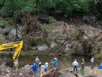 Members of a search and rescue team search for missing people amid debris in the waters of the Guadalupe River, near Camp Mystic.