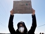 A protestor holds a sign reading "Undocumented Hands Feed You!" near federal agents blocking a road during an ICE immigration raid. A protestor holds a sign reading "Undocumented Hands Feed You!" near federal agents blocking a road during an ICE immigration raid.