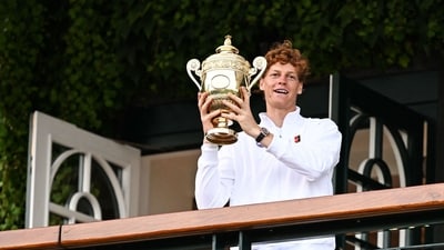 Italy's Jannik Sinner celebrates with the winner's trophy as he shows it to the crowd from the Centre Court balcony following his victory against Spain's Carlos Alcaraz at the end of their men's singles final tennis match. (AFP) Italy's Jannik Sinner celebrates with the winner's trophy as he shows it to the crowd from the Centre Court balcony following his victory against Spain's Carlos Alcaraz at the end of their men's singles final tennis match. (AFP)