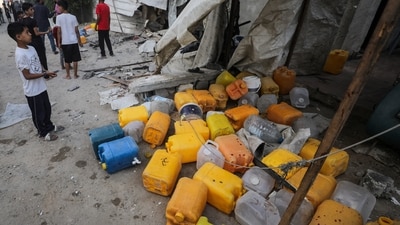 People inspect the site of an Israeli strike that killed Palestinians, gathered to collect water from a distribution point (Reuters)