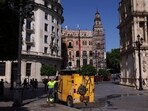 A worker holds a water flexible tube next to a small Lipasam truck during a heatwave, in Seville, Spain on July 3, 2025.