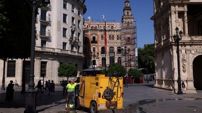 A worker holds a water flexible tube next to a small Lipasam truck during a heatwave, in Seville, Spain on July 3, 2025. (REUTERS)