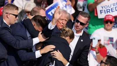 Donald Trump gestures with a bloodied face while he is assisted by US Secret Service personnel after he was shot in the right ear during a campaign rally. (REUTERS)