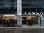 People are seen outside the Tesla showroom ahead of its opening in Mumbai.