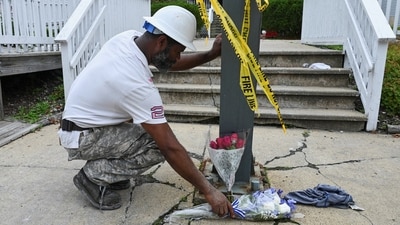A worker pauses from installing plywood to reposition bouquets of flowers in front of the Gabriel House Assisted Living Facility. (Reuters)