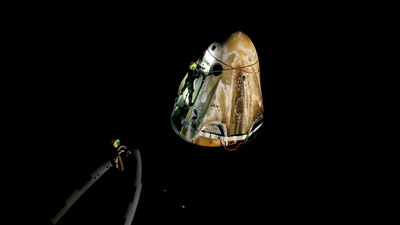 Operation personnel cling on to the exterior of the Dragon spacecraft to peg it to the jetty, which floats a few metres behind the motor boat. (Video grab/Axiom Space) Operation personnel cling on to the exterior of the Dragon spacecraft to peg it to the jetty, which floats a few metres behind the motor boat. (Video grab/Axiom Space)