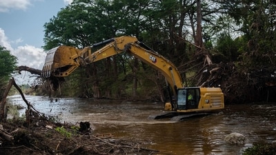 An industrial excavator is being used to remove debris off the banks of the Guadalupe river, where the alarmingly rising water level triggered the devastating Texas floods. (Jim Vondruska/AFP) An industrial excavator is being used to remove debris off the banks of the Guadalupe river, where the alarmingly rising water level triggered the devastating Texas floods. (Jim Vondruska/AFP)