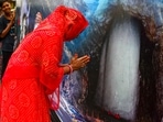 A pilgrim prays before a banner featuring the Amarnath cave shrine. A pilgrim prays before a banner featuring the Amarnath cave shrine.