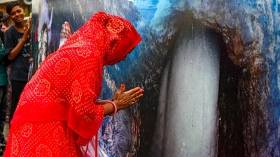 A pilgrim prays before a banner featuring the Amarnath cave shrine. (PTI) A pilgrim prays before a banner featuring the Amarnath cave shrine. (PTI)
