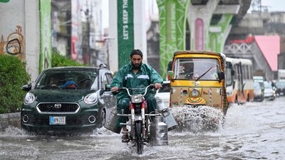 Commuters make their way through a flooded street during heavy monsoon rains in Rawalpindi on July 17, 2025. (AFP)