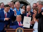  President Donald Trump holds his signed signature bill of tax breaks and spending cuts at the White House.