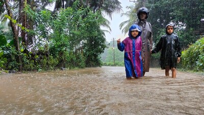 A man along with children walks through a waterlogged street during rains, in Karnataka. (File pic) (PTI) A man along with children walks through a waterlogged street during rains, in Karnataka. (File pic) (PTI)