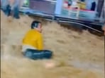 The man, who was holding a water bottle, was swept away by the current of the floodwaters. The man, who was holding a water bottle, was swept away by the current of the floodwaters.