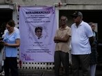 People stand next to a condolence banner as they wait for the body of Sumeet Sabharwal, captain of the Air India Boeing 787-8 Dreamliner that crashed on June 12. 