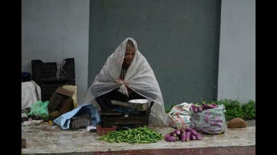 A vegetable vendor speaks on his mobile phone while the monsoon rain in Jammu on Monday. (AP)