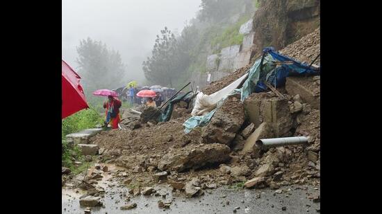 People negotiating debris on foot as a landslide blocked the Tutu-Kunihar road after heavy rain in Solan district on Monday. (HT Photo)