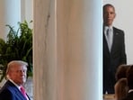Donald Trump looks on as the portrait of Barack Obama can be seen in the background.