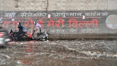 Commuters make way beside tides forming inside a waterlogged underpass, which has a muralled wall partly reading ‘Jahan mere haq ka ayushman card na banein, kya yeh hai meri Dilli,’ translating to: Where I am not able to get my Ayushman card, is this my Delhi? (Raj K Raj/HT) Commuters make way beside tides forming inside a waterlogged underpass, which has a muralled wall partly reading ‘Jahan mere haq ka ayushman card na banein, kya yeh hai meri Dilli,’ translating to: Where I am not able to get my Ayushman card, is this my Delhi? (Raj K Raj/HT)