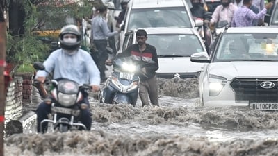 A commuter pushes his scooter through a dangerously waterlogged road, jammed with vehicles in the drenched national capital city, Delhi. (Sanchit Khanna/Hindustan Times)