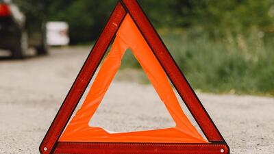 Driver putting warning triangle on asphalt road. Emergency stop concept.