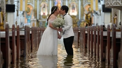 Newlyweds Jade Rick Verdillo right, and Jamaica kiss during their wedding at the flooded Barasoain church in Malolos. (AP) Newlyweds Jade Rick Verdillo right, and Jamaica kiss during their wedding at the flooded Barasoain church in Malolos. (AP)