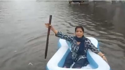 A woman rowing a 'boat' in rainwater in an X post by former Delhi CM Atishi. (X/@AtishiAAP) A woman rowing a 'boat' in rainwater in an X post by former Delhi CM Atishi. (X/@AtishiAAP)