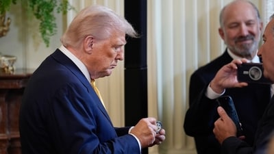 Donald Trump holds a challenge coin while greeting attendees during a reception with Republican members of Congress in the East Room of the White House on Tuesday, July 22, 2025. (Bloomberg) Donald Trump holds a challenge coin while greeting attendees during a reception with Republican members of Congress in the East Room of the White House on Tuesday, July 22, 2025. (Bloomberg)